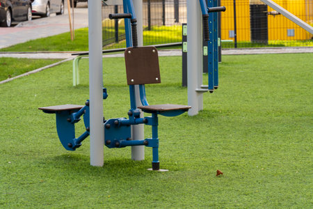 Various gym machines are positioned on artificial grass in a community park, encouraging outdoor...