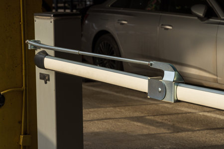 An automatic barrier gate stands closed at the entrance of a parking lot, ensuring controlled access...