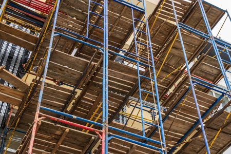 Workers utilize scaffolding to build a multi-story structure, showcasing essential equipment in the construction industry at a bustling site.の写真素材