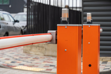 An automatic barrier gate stands closed, controlling entry to a well-organized parking lot, ensuring...