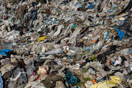 A vast expanse of mixed trash and debris covers a landfill, highlighting environmental challenges...