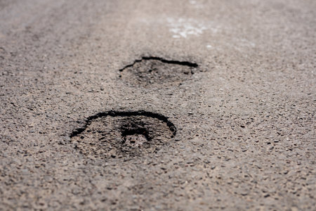 Cracks in the asphalt along a highway highlight areas that require immediate maintenance and repair to ensure driver safety.の写真素材