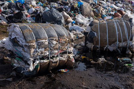 Debris and waste piled high at a landfill with compressed bales, emphasizing the urgency of proper waste disposal and environmental care.の写真素材