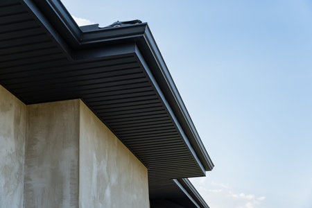 A detailed view of a building's rooftop with sleek metallic tiles and smooth lines against the blue...
