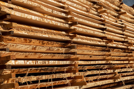 Neatly stacked wood planks in a lumber yard illustrate the beauty of natural textures and grains...