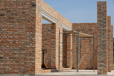 Brick walls are being erected for a new residential building with scaffolding present at the...