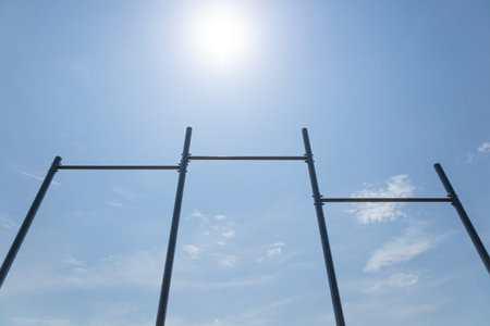 Metal scaffolding stands against a clear blue sky with sunlight illuminating the scene and soft...