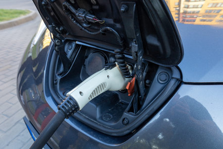 A modern electric vehicle is being charged at a public charging station, showcasing the power...