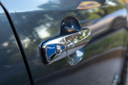 This close-up captures the sleek design of a car door handle reflecting sunlight while highlighting its metallic finish.の写真素材