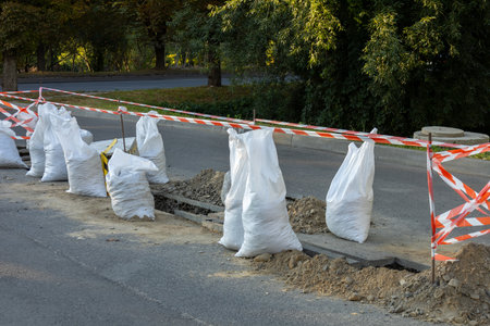 Construction work is taking place along the roadway with sandbags and safety barriers marking the area for public safety.の写真素材