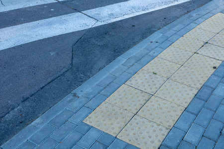 Sidewalk pavement transitions to textured crosswalk area designed for pedestrian safety and accessibility on a city street.の写真素材