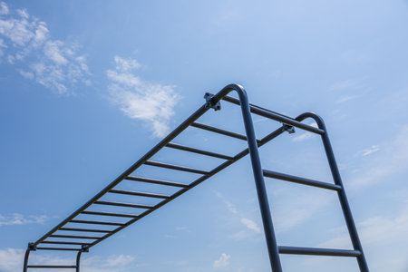 Active individuals train on a horizontal bar in a sunny park, focusing on fitness and exercise in an outdoor setting.の写真素材