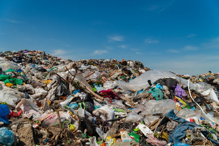 A large landfill showcases heaps of trash and waste, revealing the impact of pollution on the environment under a bright sky.の写真素材