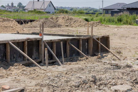 Workers are setting up a foundation slab for a new house in a developing neighborhood, with dirt and...