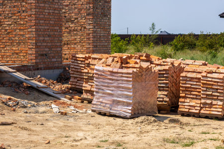 Bricks neatly stacked on pallets at a construction site, indicating ongoing development of new...