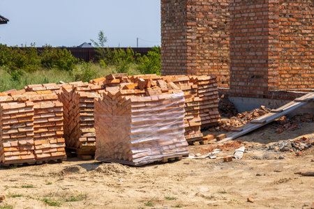 Bricks are neatly stacked on a construction site, prepared for building homes in a growing...