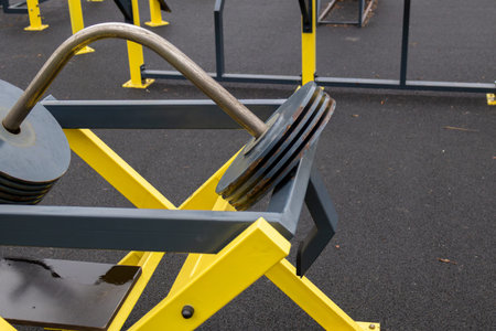 Heavy weight plates rest on a sturdy outdoor gym frame designed for strength training in a public...