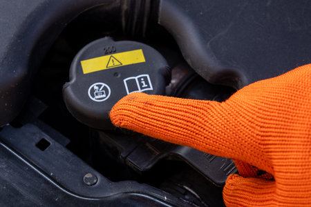 A mechanic points at the radiator cap to explain its location and function while working in a garage on a bright day.の写真素材