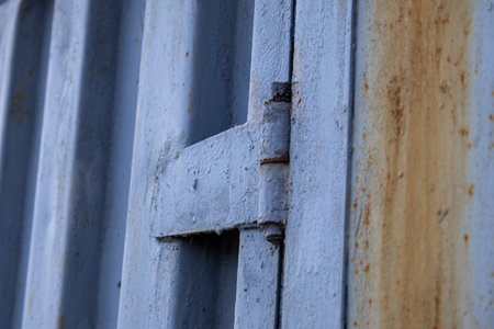 A metal gate is shown from a close angle, highlighting the texture and rust on the surface in a residential area during late afternoon light.の写真素材