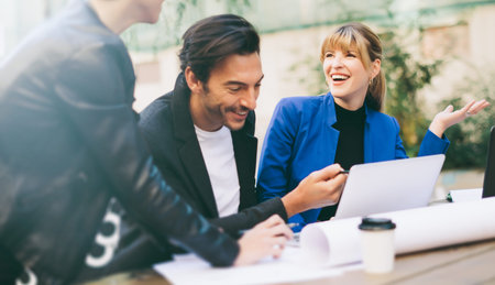 Group of people sitting around table outdoor, talking and working togetherの写真素材