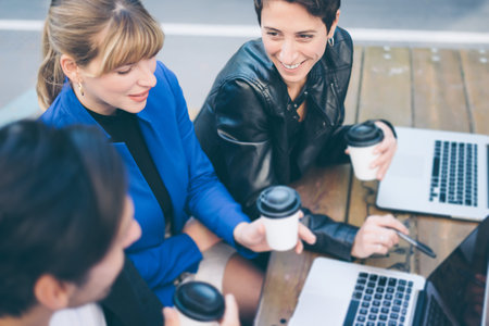 Group of people sitting around table outdoor, talking and working togetherの写真素材