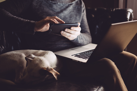 Man with his dog and laptop works at homeの写真素材