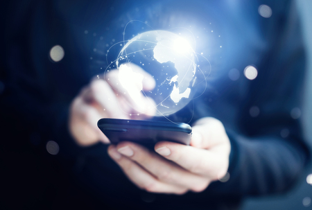 Man using smartphone with abstract globe at workplaceの写真素材