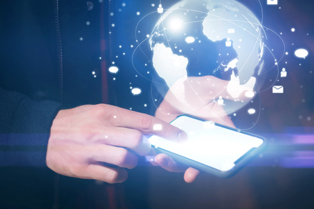 Man using smartphone with abstract globe at workplaceの写真素材