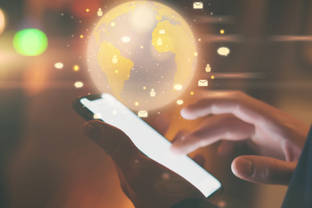 Man using smartphone with abstract globe at workplaceの写真素材