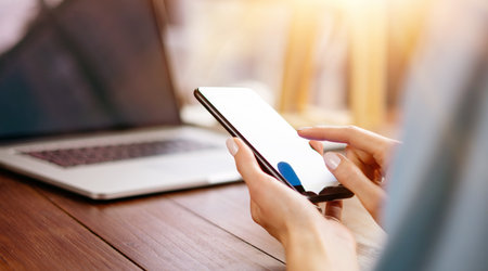 Woman pointing on smartphone screen, chatting in social networks, meeting website, searching internet, sending sms, using text messenger or online banking. Close up of female hands with mobile phoneの写真素材