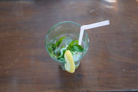 Top view of an empty glass with lime, mint, straw and ice mojito drink on a table.の写真素材