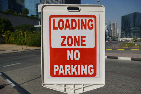 Dubai UAE December 2019 Red and white sign for no parking in the loading zone outside a building. Residential and commercial area with No Parking, Loading Zone sign.のeditorial素材