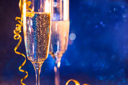 Christmas and New Year holiday background with two goblet,wine glass champagne and blue bokeh effect background. Happy New Year!の写真素材