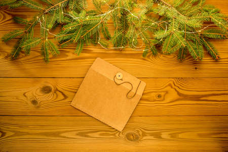 Brown envelope with fir branches on wooden table.Festive concept.Flat layの写真素材