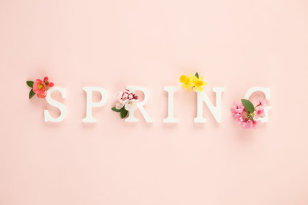 White wooden letters make up the spring composition with fresh spring flowers. Minimal concept. Top...