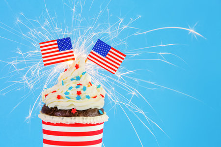 Independance Day or USA theme party food.Cupcake with American Flags and sparkler and blue...
