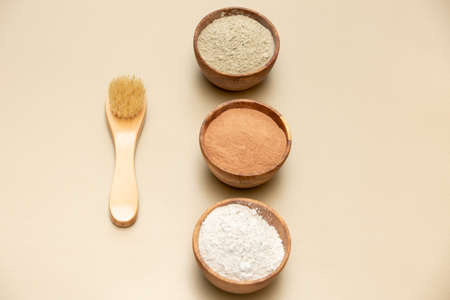 Organic green, red, white face mask clay in wooden bowls with bamboo and goat hair brush on beige background. Home skin care concept.Self careの写真素材
