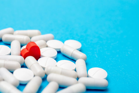 Red pill in the shape of a heart on a background of white pills and a blue background. The concept of love addiction, love drugs, Valentines Day and depressionの写真素材