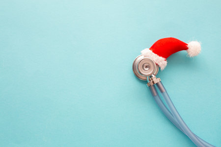 Medical stethoscope in a red Santa Claus hat, blue background. Christmas and new year concept. Creative medical winter background, postcard.Close upの写真素材