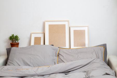 Workplace in bed. Laptop with glasses on the bed on gray bedding and yellow pillows. Modern and comfortable bedroom, home office background. The concept of working from home.の写真素材
