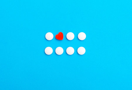 Red pill in the shape of a heart on the background of white pills and a blue background. The concept...