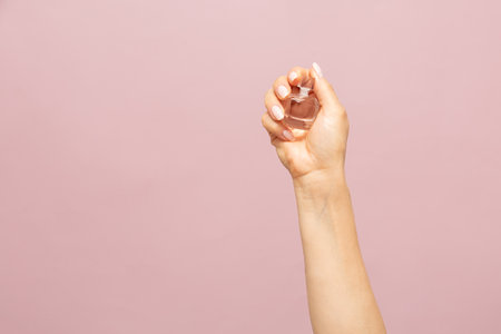 Female wearing romantic vintage rose blouse with black polka dots. Holding perfume bottle in her hand. Perfume half full. Rose and orange liquid. Workshop banner for perfumers. High-quality photoの写真素材