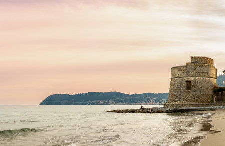 Historic Saracen tower on the Mediterranean beach of Alassio, ancient defensive bastion built in the 16th century on the seashore, with Capoの写真素材