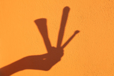 Beautiful female hand holding a set of makeup brushes on a yellow background in the shape of a sun shadow Setの写真素材
