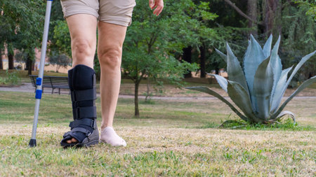 A woman unrecognizable with her leg fractured on the bed with the support stabilizes Walker, reads a book, the recovery from the trauma ofの写真素材