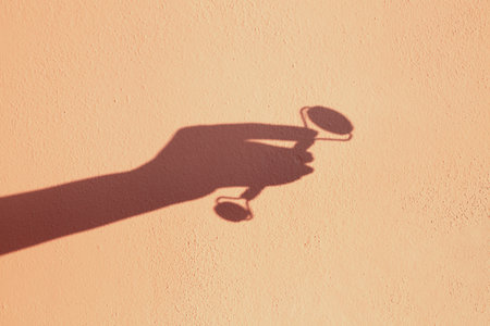 Jade roller for facial aesthetic massage on yellow background with shadow created by sun. Jade roller skin care for face.の写真素材