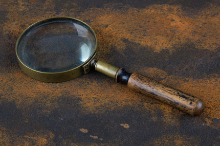 Vintage magnifying glass on rusty metal surface coated with corrosion.の写真素材