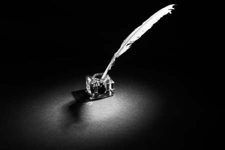 Quill pen with inkwell on a black textured backgroundの写真素材
