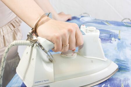 Humdrum of housewife. photo with a smoothing iron and handcuffsの写真素材