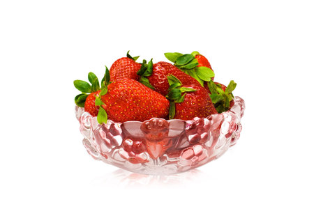 Several strawberrys in decorative glass vase with reflection at bottomの写真素材